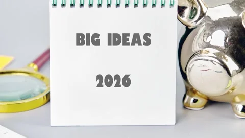 A notepad displays BIG IDEAS 2026 beside a golden Piggy Bank. a magnifying glass Stock Footage 319735461
