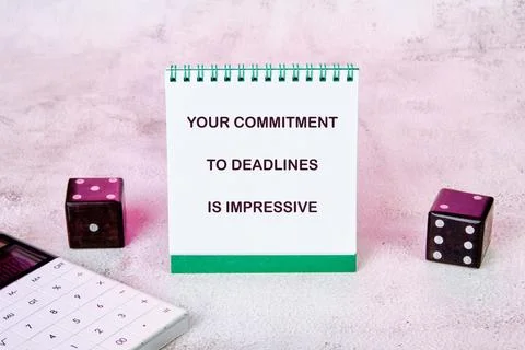 A notepad displays the message about commitment to deadlines while a calculat Stock Photos