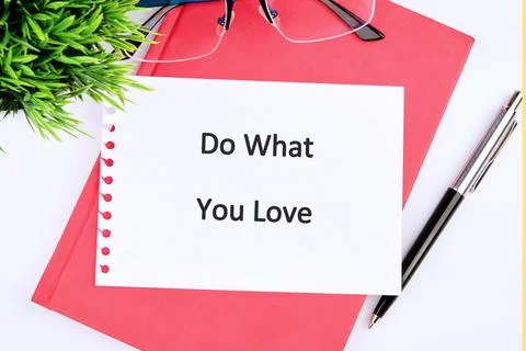A notepad displays the motivational message Do What You Love, sitting on a red Stock Photos