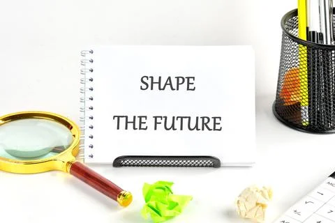A notepad displays SHAPE THE FUTURE alongside a magnifying glass and colorful Foto stock