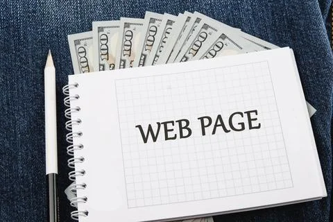 A notepad displays a web page layout while cash is neatly arranged in the bac Stock-Fotos
