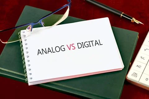 A notepad displays the words analog vs digital, sharing a desk with glasses a Stock Photos