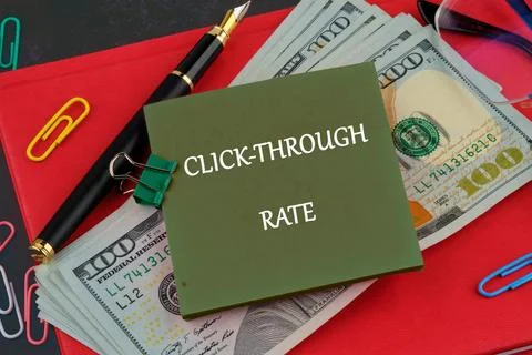 A notepad displays the words click-through rate beside dollar bills and offic Stock Photos