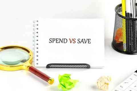 A notepad displays the words spend vs save. Nearby are a magnifying glass, cr Stock Photos