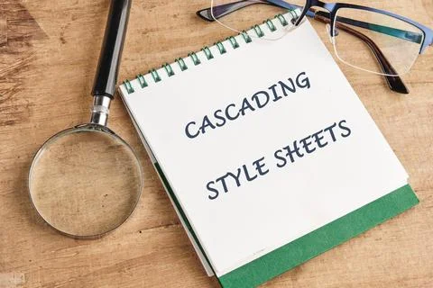 A notepad featuring the text Cascading Style Sheets is placed on a wooden sur Stock Photos