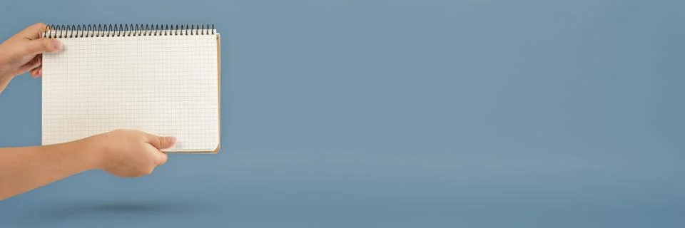 Notepad in hand. Blank notepad in the hands on a blue background. Hands hold a Stock Photos