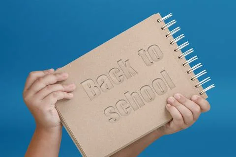 Notepad in hand with text back to school. Notepad in the hands of a child on a Stock Photos