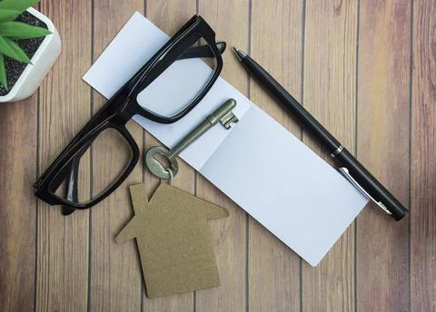 Notepad with house model and key on wooden desk. Directly above. Flat lay. Stock Photos