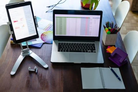 Notepad, laptop and tablet with spreadsheet and document on screen, on dining Stock Photos