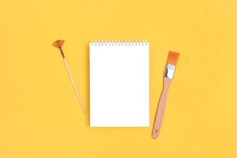 Notepad mockup with paint brushes on a bright yellow background. Stock Photos