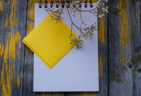 Notepad for notes and white flowers on a yellow background, top view Stock Photos