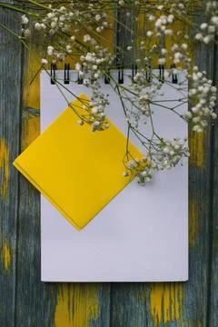 Notepad for notes and white flowers on a yellow background, top view Stock Photos