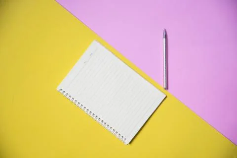 Notepad or notebook paper with pen on yellow pink background top view for edu Stock Photos