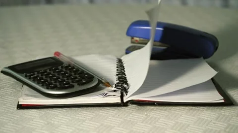 Notepad paper blowing in office with calculator Stock Footage 314834235
