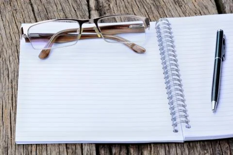 Notepad with pen and eyeglasses on table Stock Photos