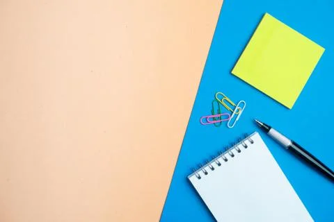 Notepad with pen and yellow note sticks on blue and orange background. Colorf Stock Photos