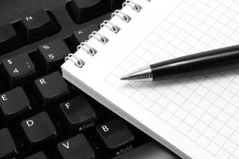 Notepad with pen on a black computer keyboard Stock Photos