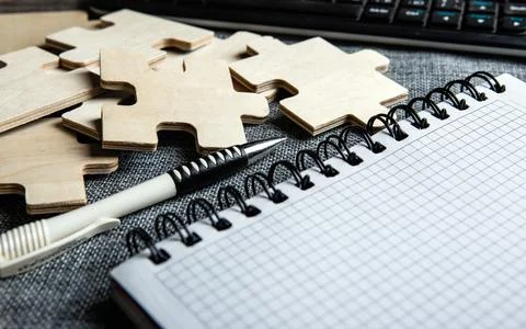 Notepad with a pen, pc keyboard and puzzle pieces Stock Photos