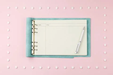 Notepad with pen on pink desk. Stock-Fotos