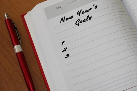 Notepad with a pen on a wooden table. View from above. The concept of goals for Stock Photos