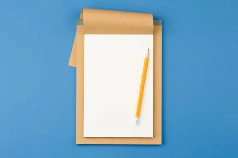 Notepad with pencil on blue background. Stock Photos