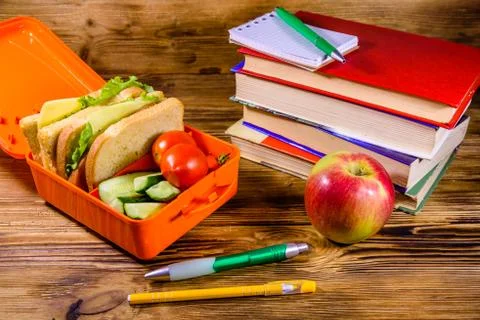 Notepad, pens, ripe apple, stack of books and lunch box with sandwiches, cucu 스톡 사진