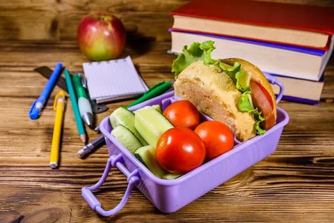 Notepad, pens, ripe apple, stack of books and lunch box with hamburger Stock Photos