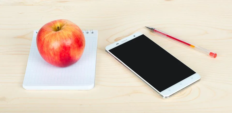 Notepad the phone and the apple on the table Stock Photos