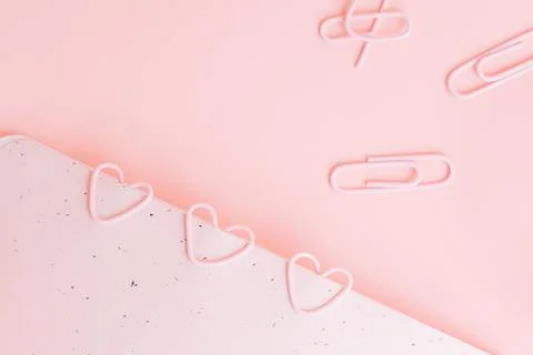 Notepad with pink paper clips in the shape of hearts on a pink background Stock Photos