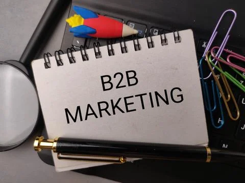 A notepad reading B2B MARKETING rests on a black keyboard alongside a pen, .. Fotos de archivo