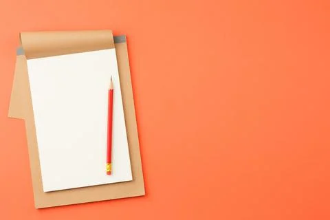 Notepad with red pencil on orange background Stock Photos