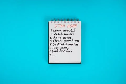 Notepad with self isolation check list on the blue background. Stay home-stay Stock Photos