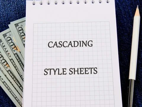 A notepad showcases the term Cascading Style Sheets, surrounded by currency.. Stock Photos