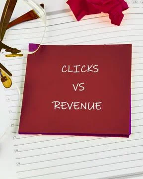 A notepad shows the words clicks versus revenue. Glasses rest on the page. .. Stock Photos