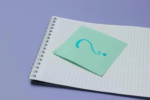 Notepad with a sticky note showing a question mark on purple background Stock Photos