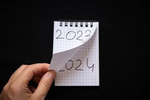 Notepad with text 2023 and 2024 and the hand turns the page of the notepad,.. Stock Photos
