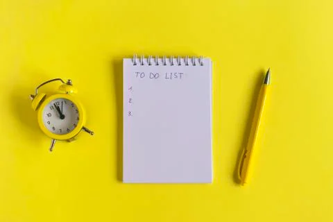 Notepad with text "to do list", clock and pen on a yellow background, spiral  Stock Photos