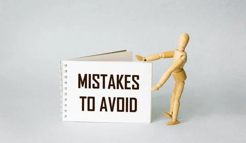 Notepad with text errors to avoid with a wooden doll on a light background. C 写真素材