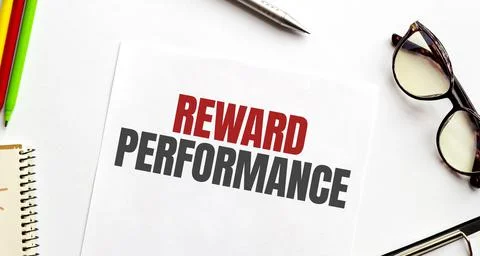 Notepad with text REWARD PERFORMANCE , on business charts and pen and charts Foto stock
