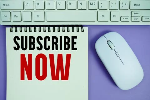 Notepad with the text "Subscribe Now" and white keyboard and wireless mouse.. Stock Photos