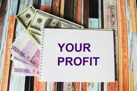 Notepad with the text YOUR PROFIT, dollars and euros lie on a colored striped Stock Photos