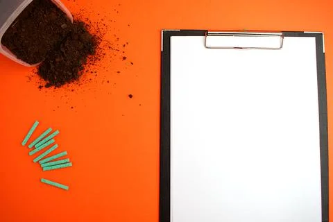 Notepad with a white sheet of paper, next to the ground and green fertilizer  Stock Photos