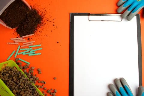 Notepad with a white sheet of paper, next to the ground, garden gloves, clay  Stock Photos