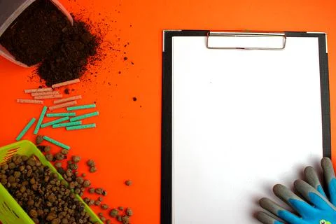 Notepad with a white sheet of paper, next to the ground, garden gloves, clay  Stock Photos