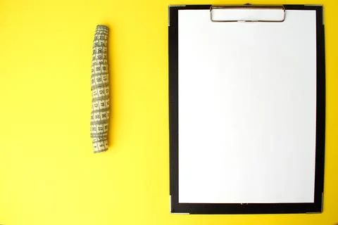 Notepad with a white sheet of paper for notes, next to it twisted centimeter Stock Photos