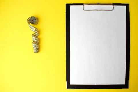 Notepad with a white sheet of paper for notes, next to it twisted centimeter Stock Photos