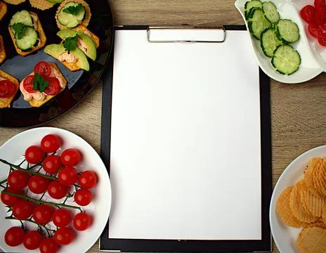 Notepad with a white sheet of paper for notes. Around a snack of crackers Stock Photos