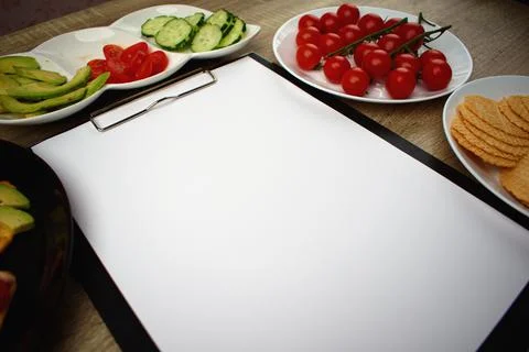 Notepad with a white sheet of paper for notes. Around a snack of crackers Stock Photos