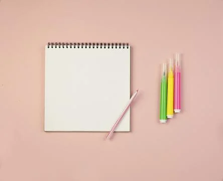Notepad with white sheets and a pen and markers on a pink background Stock Photos