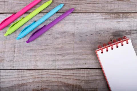 Notepad with white sheets and set of colored pens on wooden background Stock Photos
